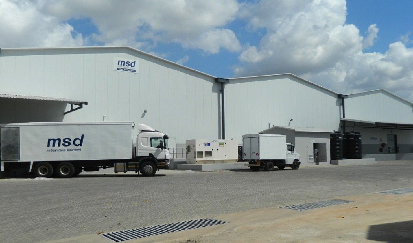 A completed white medical storage warehouse with MSD branding, with MSD delivery trucks at the loading bays and a paved yard in the foreground